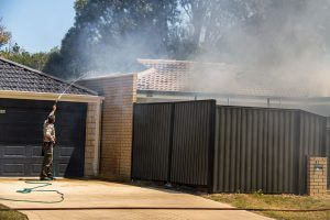 John Geerlings, who was visiting a family member in the street, hoses down a stranger's home to stop the fire from spreading. Photograph - Robyn Molloy.